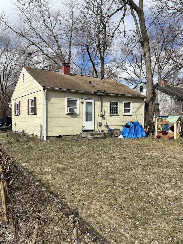 rear view of house with a shingled roof, a chimney, and entry steps