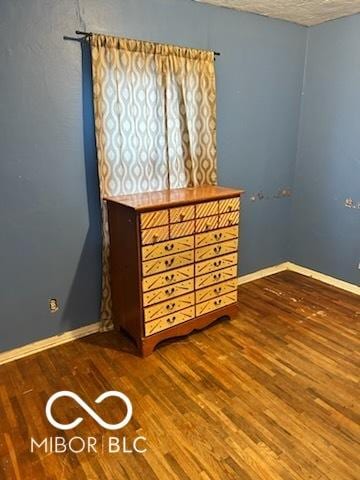 spare room featuring baseboards and wood finished floors