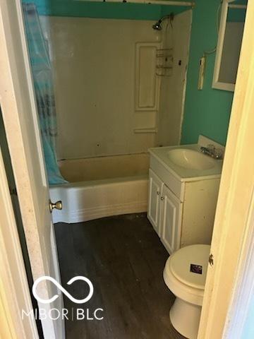 full bathroom featuring toilet, shower / tub combo with curtain, wood finished floors, and vanity