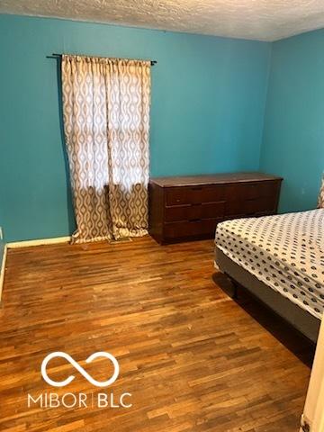 unfurnished bedroom with a textured ceiling and wood finished floors