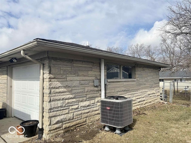 view of property exterior featuring stone siding, an attached garage, cooling unit, and fence