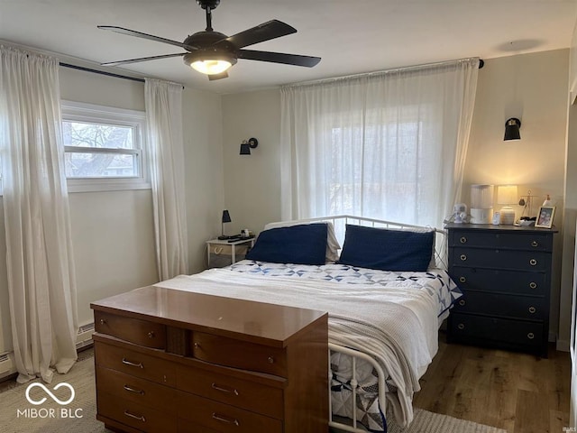 bedroom featuring ceiling fan, a baseboard radiator, and light wood-style floors