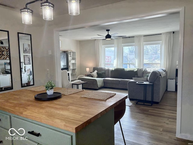 kitchen with butcher block countertops, wood finished floors, visible vents, a ceiling fan, and open floor plan