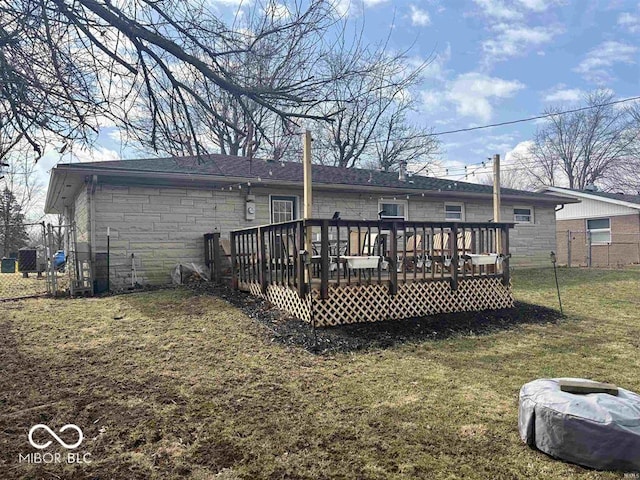 back of property featuring a deck, a yard, stone siding, and fence