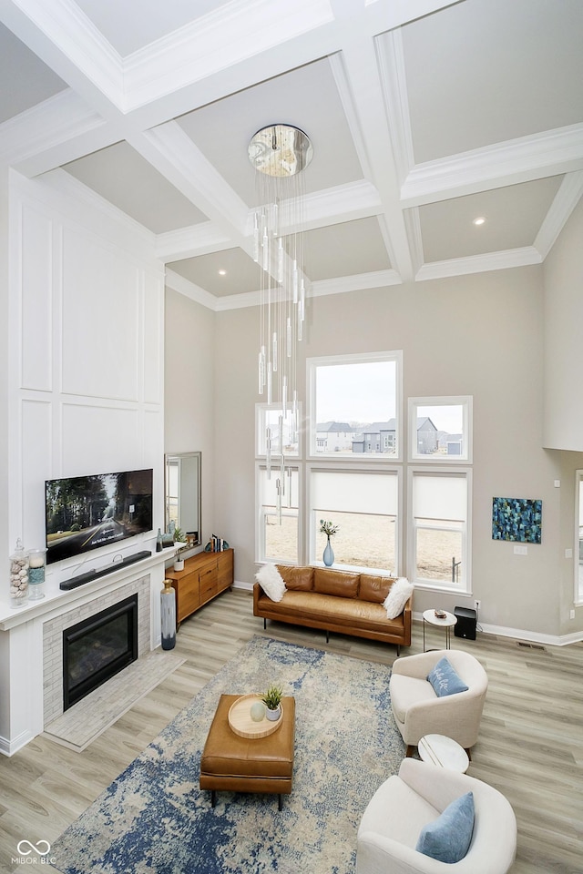 living room with beam ceiling, light wood finished floors, a large fireplace, coffered ceiling, and baseboards