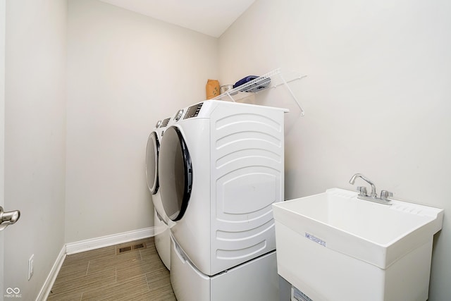 laundry area featuring laundry area, separate washer and dryer, a sink, visible vents, and baseboards