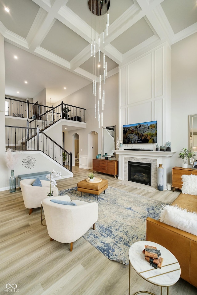 living area with arched walkways, stairway, wood finished floors, and a towering ceiling