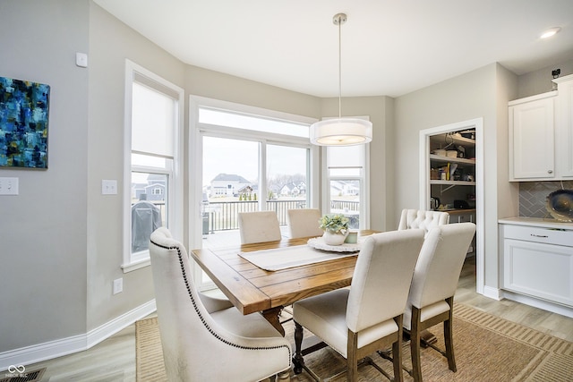 dining space with light wood-style flooring, visible vents, and baseboards