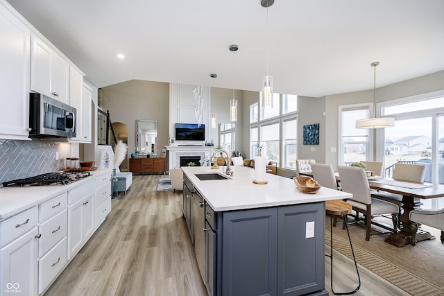 kitchen featuring a breakfast bar, a sink, white cabinets, appliances with stainless steel finishes, and tasteful backsplash