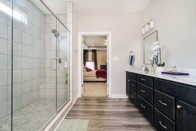 ensuite bathroom with ensuite bathroom, a sink, wood finished floors, a shower stall, and double vanity