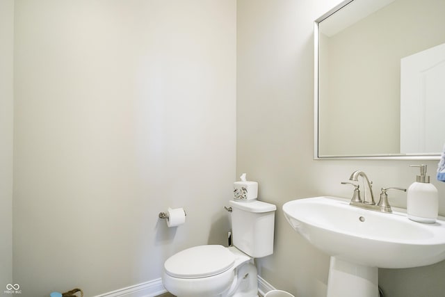 bathroom featuring a sink, toilet, and baseboards