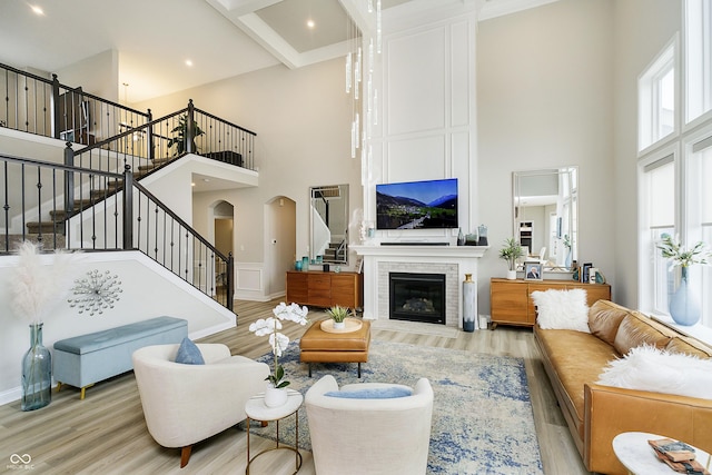 living room with a high ceiling, stairway, a fireplace, and wood finished floors