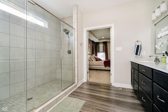 full bath featuring connected bathroom, a shower stall, vanity, and wood finished floors