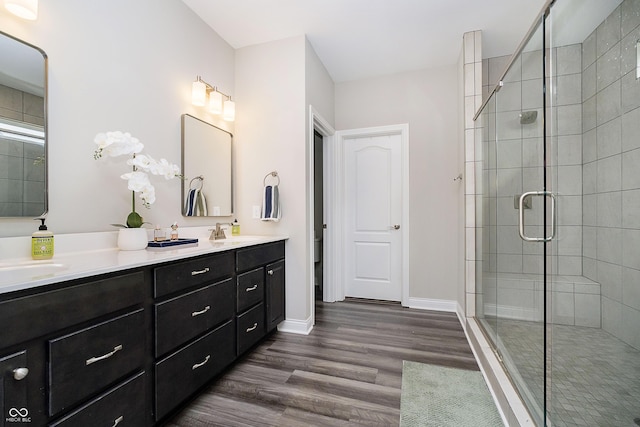 bathroom with wood finished floors, a stall shower, a sink, and baseboards