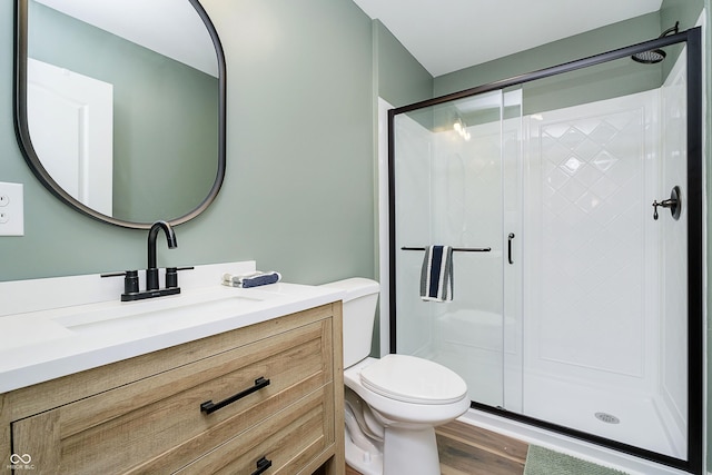 bathroom featuring vanity, wood finished floors, a shower stall, and toilet