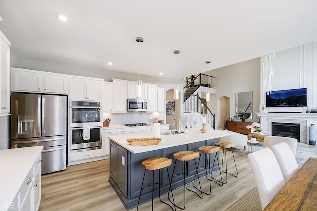 kitchen with arched walkways, a fireplace, a sink, appliances with stainless steel finishes, and decorative backsplash