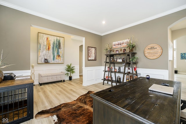 home office featuring arched walkways, crown molding, wainscoting, and light wood-style floors