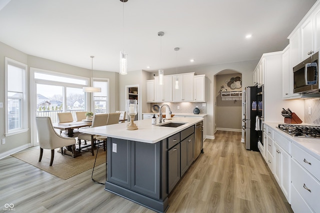 kitchen with appliances with stainless steel finishes, light countertops, white cabinets, and a sink