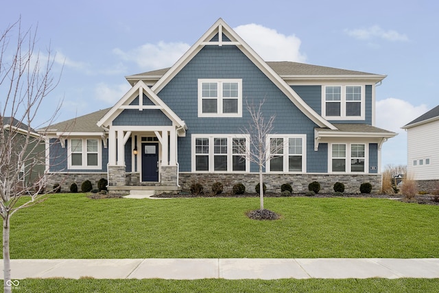 craftsman house with stone siding, roof with shingles, and a front lawn