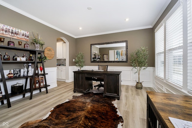 home office with ornamental molding, arched walkways, wainscoting, and light wood-style floors