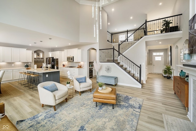 living room featuring light wood-type flooring, stairway, arched walkways, and recessed lighting