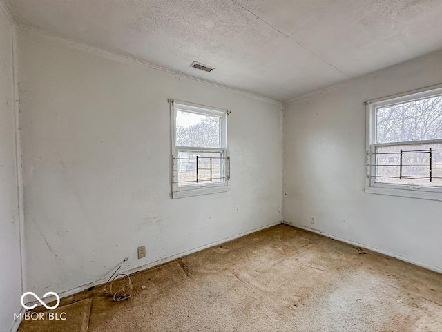 carpeted spare room featuring visible vents and a textured ceiling