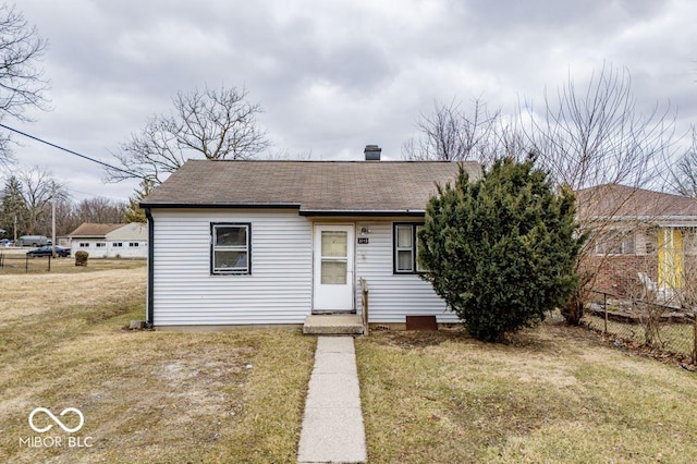 view of front of property with roof with shingles, fence, and a front yard