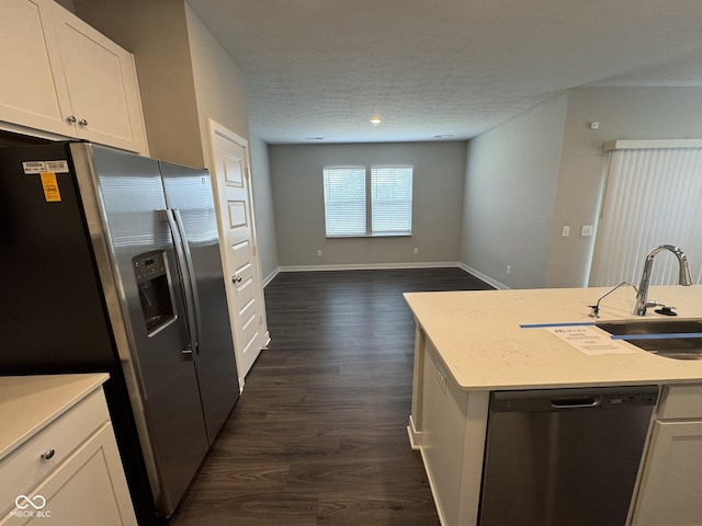 kitchen with dark wood finished floors, appliances with stainless steel finishes, light countertops, a textured ceiling, and white cabinetry