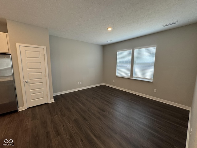 unfurnished room featuring dark wood-style floors, visible vents, a textured ceiling, and baseboards