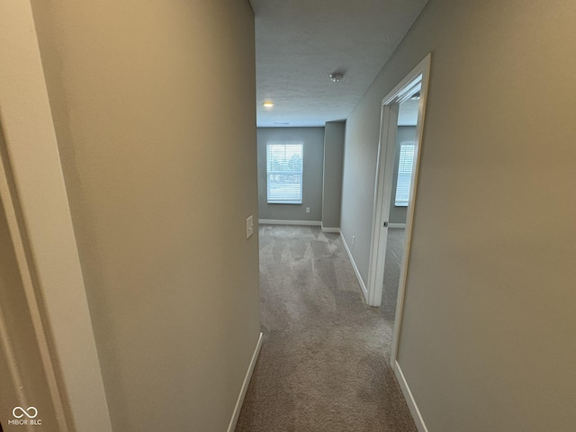 hallway featuring carpet and baseboards