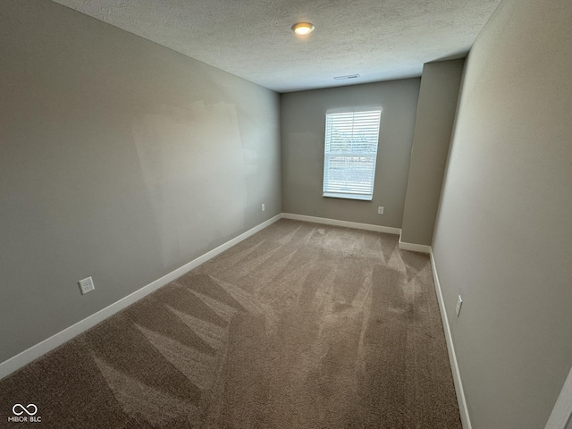 empty room featuring a textured ceiling, carpet, and baseboards