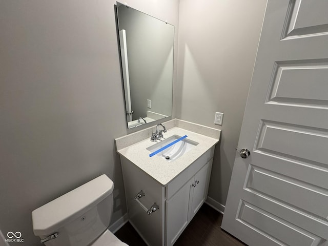 half bathroom featuring toilet, wood finished floors, and vanity