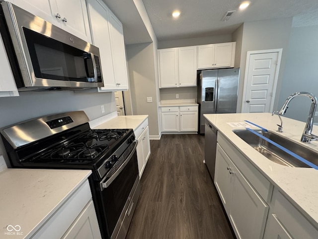 kitchen with a sink, visible vents, white cabinets, appliances with stainless steel finishes, and dark wood-style floors