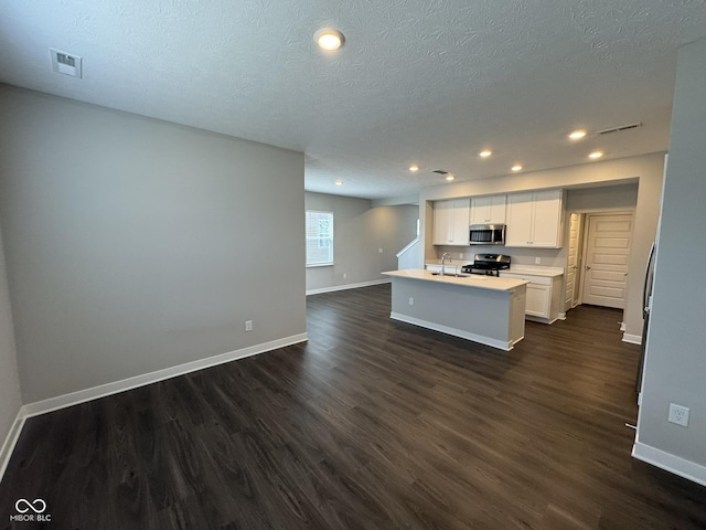 kitchen with baseboards, visible vents, dark wood-style flooring, stainless steel appliances, and white cabinetry