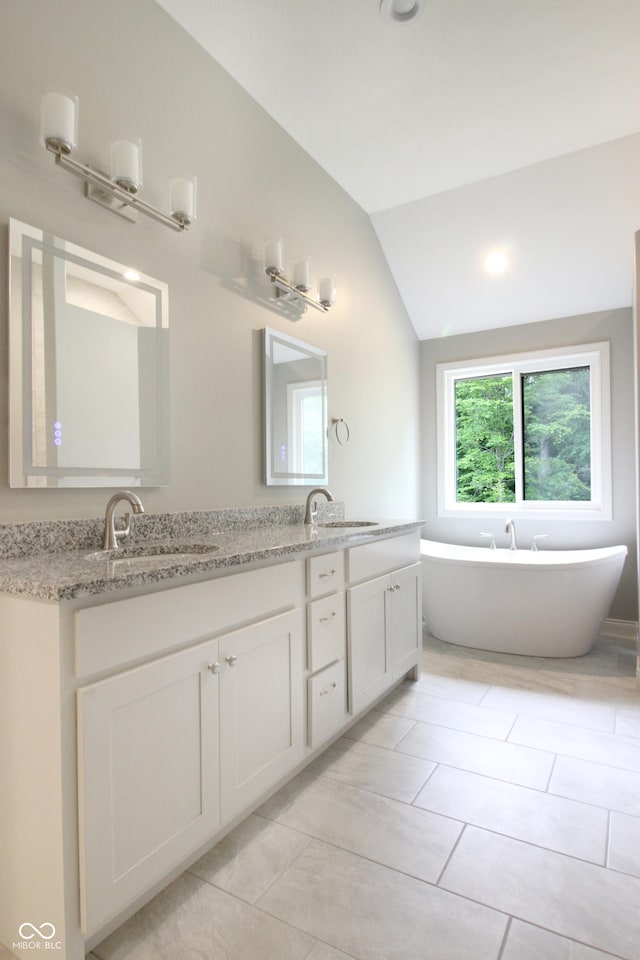 3604 Maple Ridge Dr, Columbus, IN 47201 - bathroom featuring vaulted ceiling, double vanity, a freestanding tub, and tile patterned floors