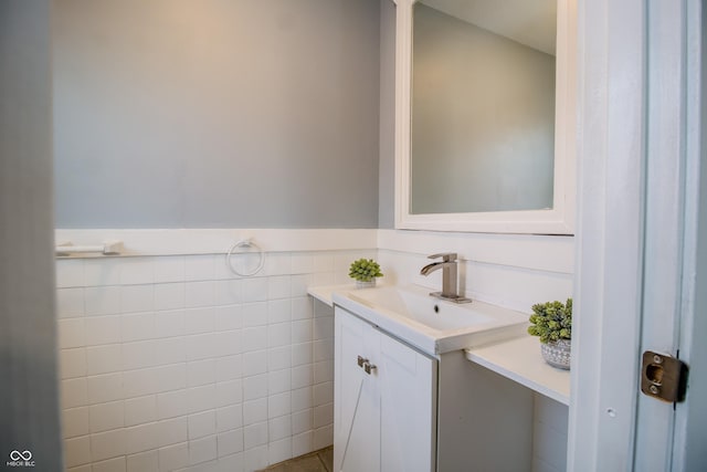 bathroom with a wainscoted wall, tile walls, and vanity