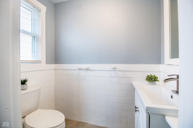 bathroom featuring tile walls, a wainscoted wall, vanity, and toilet