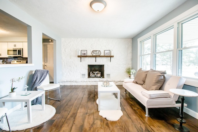 living area featuring dark wood-type flooring, a fireplace, and baseboards