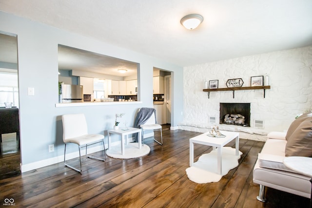 living area with visible vents, a fireplace, baseboards, and wood finished floors