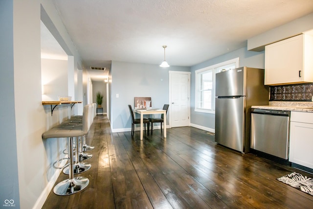 kitchen featuring dark wood-type flooring, visible vents, white cabinetry, appliances with stainless steel finishes, and backsplash