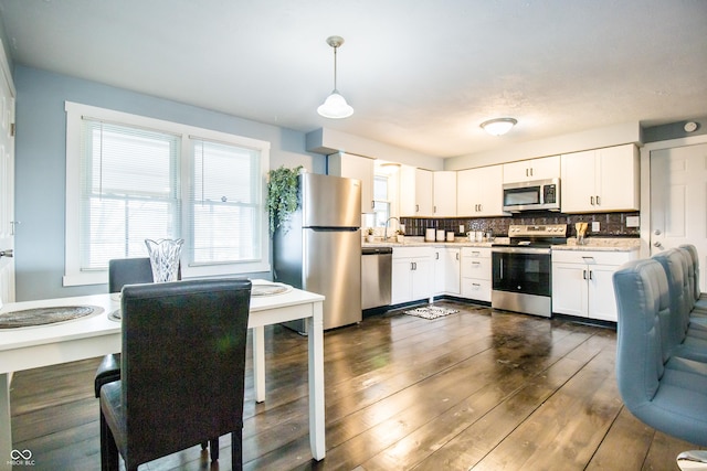 kitchen with stainless steel appliances, tasteful backsplash, light countertops, dark wood-type flooring, and white cabinetry