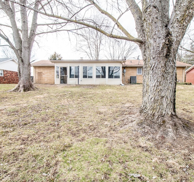 ranch-style house with brick siding, a front yard, and a sunroom