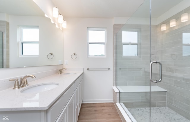 bathroom with a tile shower, wood finished floors, and a sink