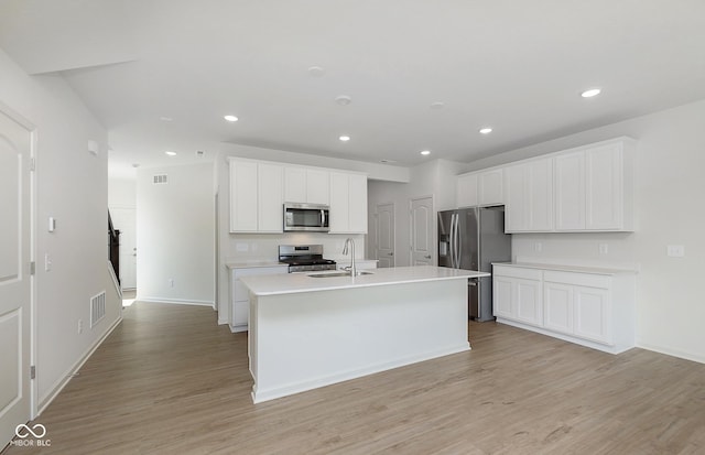 kitchen featuring stainless steel appliances, visible vents, a sink, and light wood-style flooring