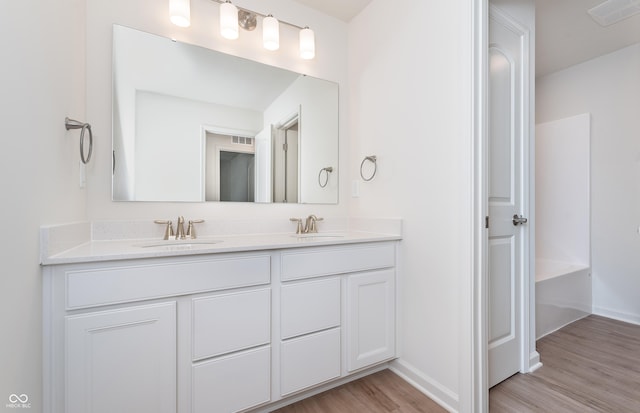 full bathroom with double vanity, wood finished floors, a sink, and visible vents