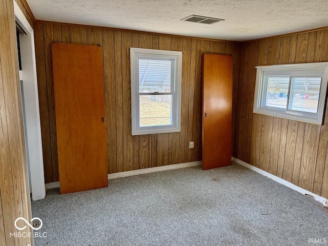 unfurnished room featuring a healthy amount of sunlight, carpet, visible vents, and a textured ceiling