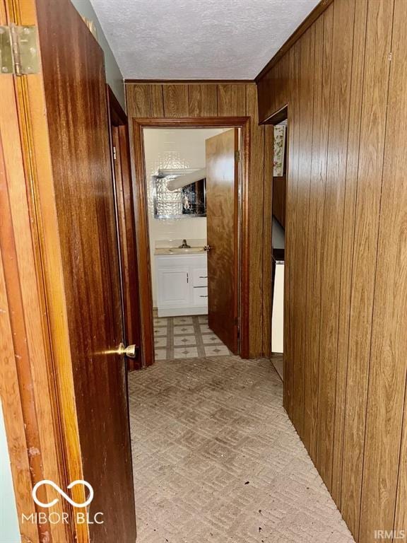 hall with a textured ceiling, wooden walls, and tile patterned floors