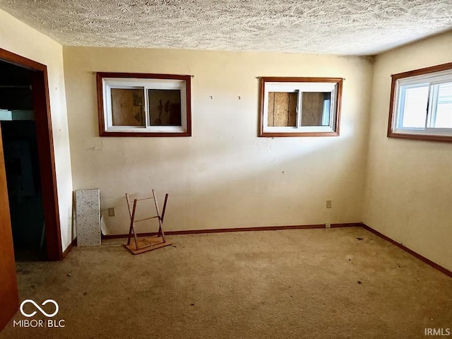 carpeted spare room featuring baseboards and a textured ceiling