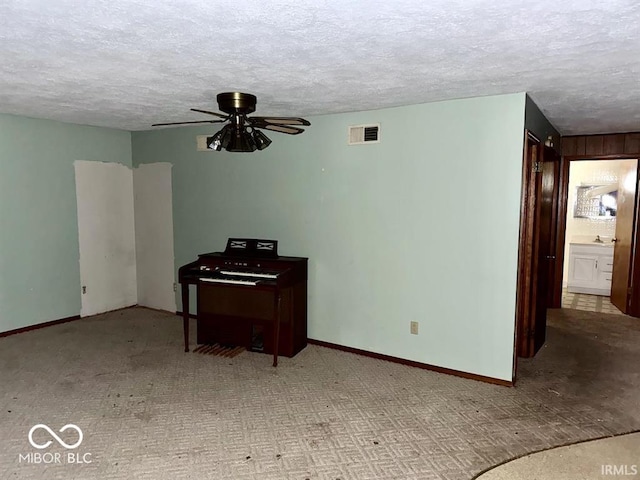 interior space featuring a textured ceiling, ceiling fan, visible vents, and baseboards