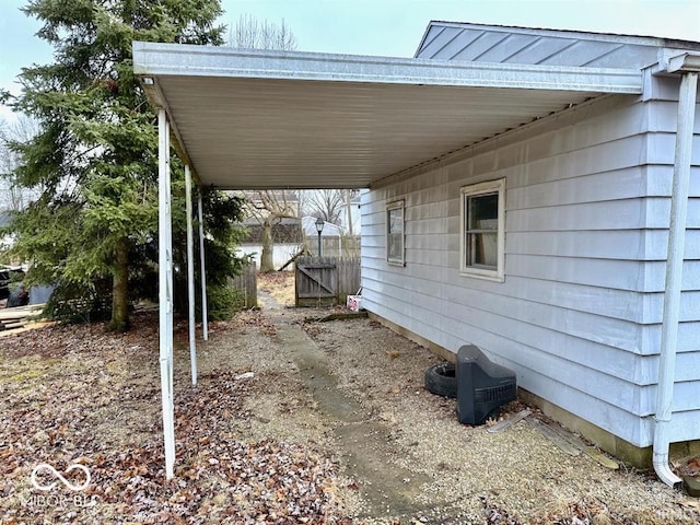 view of property exterior with an attached carport and fence